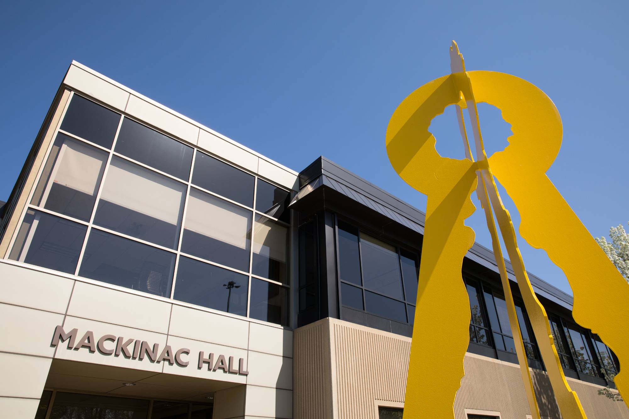 The front of Mackinac Hall and a metal yellow sculpture